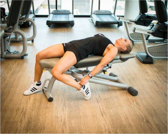Lying on a bench pulling one heel back to stretch the hip flexor