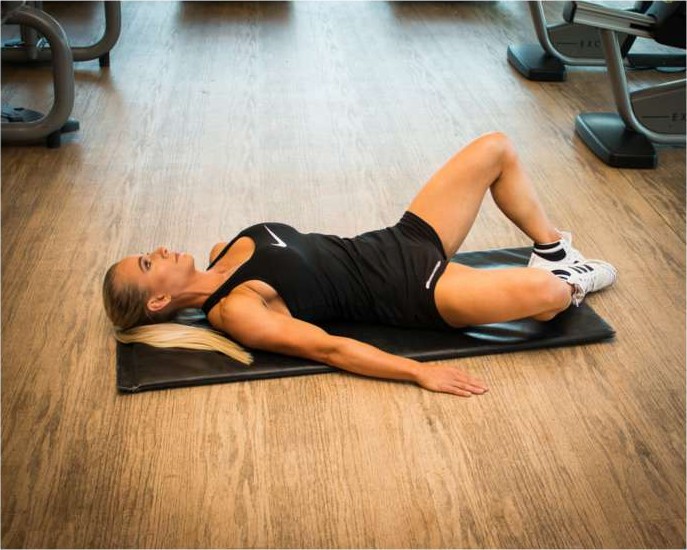 Bent knee fall out exercise lying on a mat to activate the deep core and hips