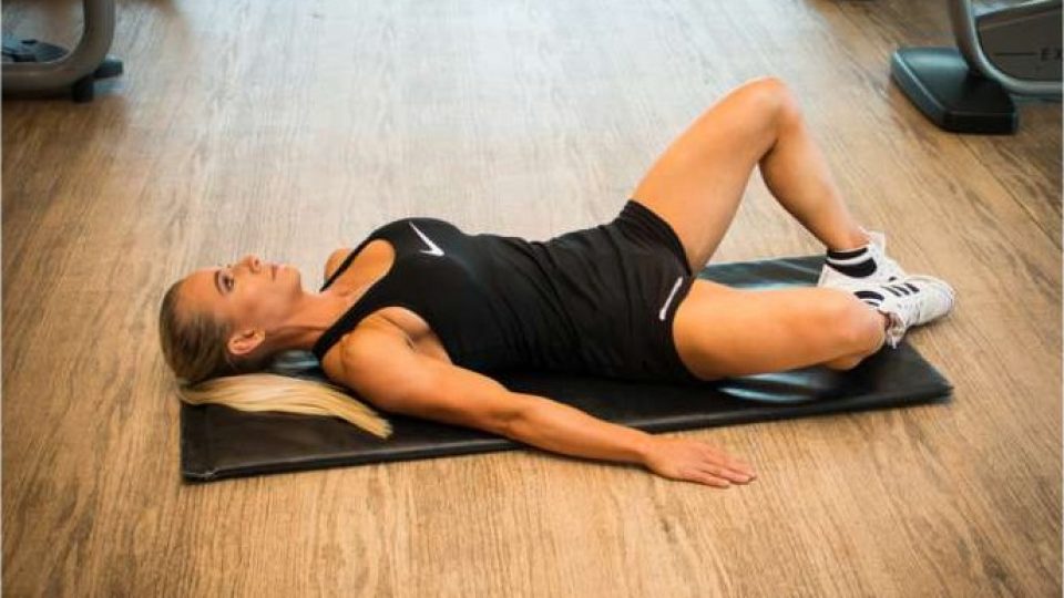 Bent knee fall out exercise lying on a mat to activate the deep core and hips